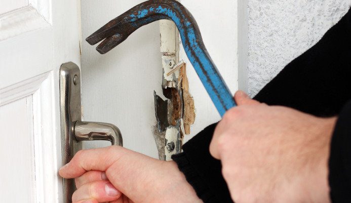 thief using crowbar to break door lock