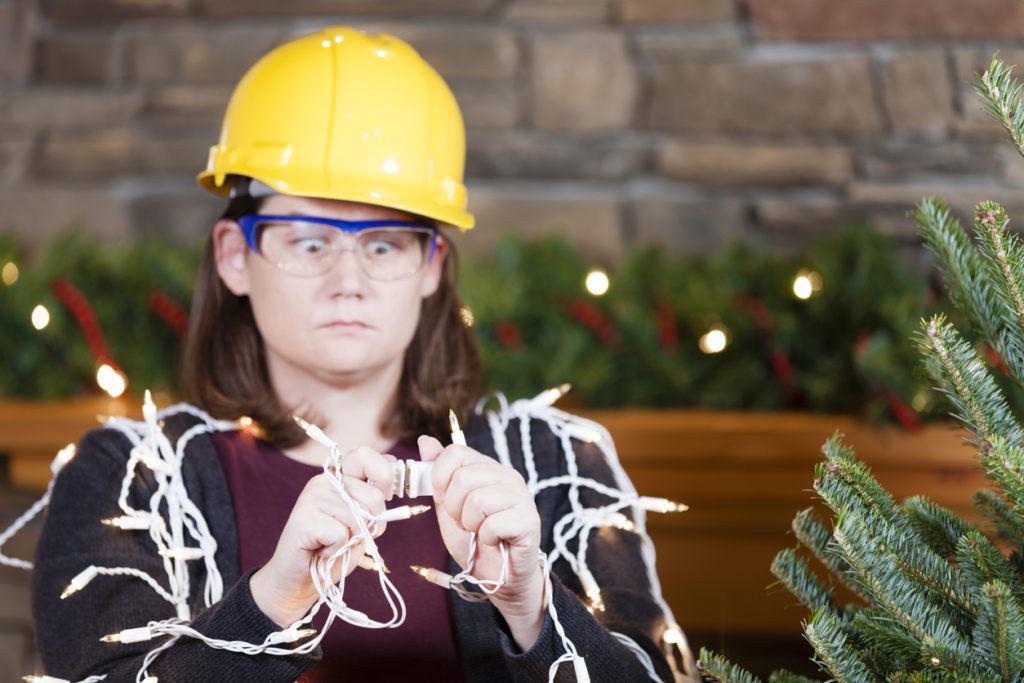 Young woman wearing hardhat and safety glasses plugging in Christmas tree lights
